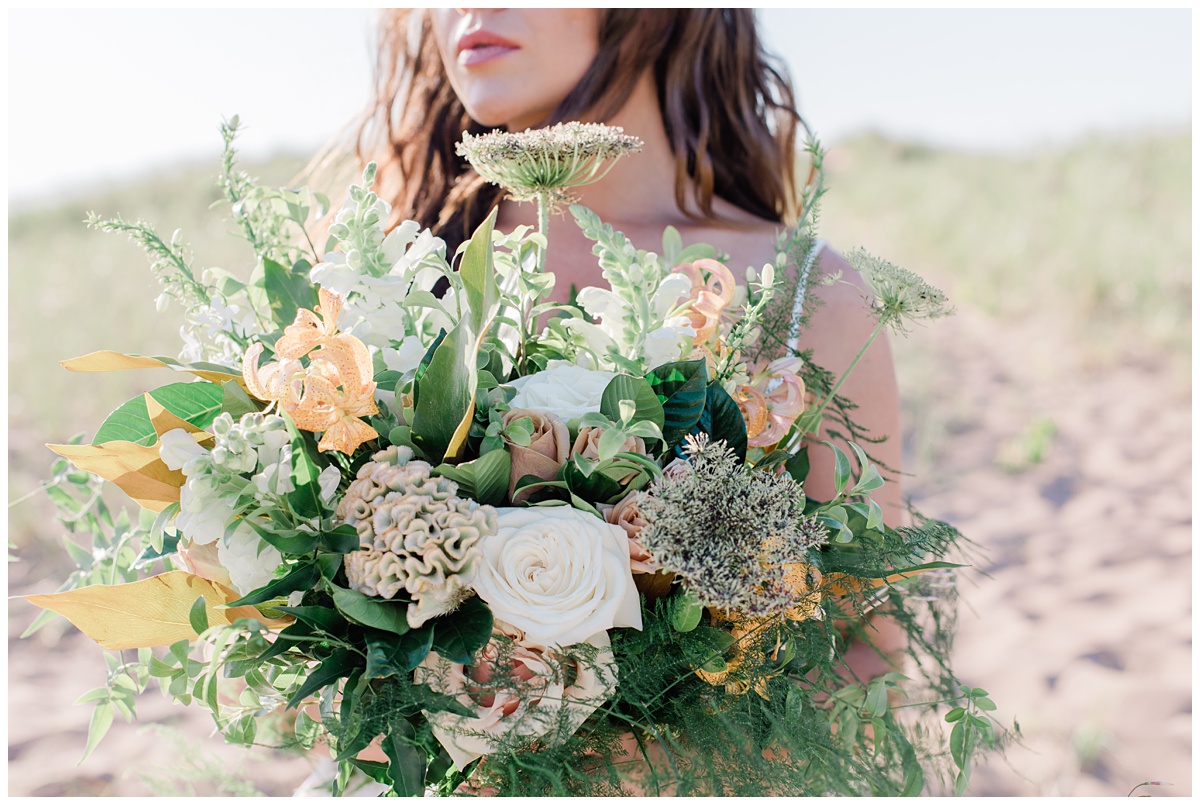 Bride holds gorgeous bouquet of peach and white flowers mixed with greenery