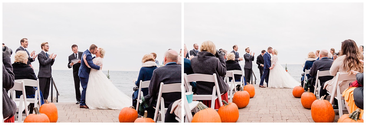 bride and groom share their first kiss as man and wife surrounded by their guests, pumpkins, and a gorgeous stormy ocean backdrop