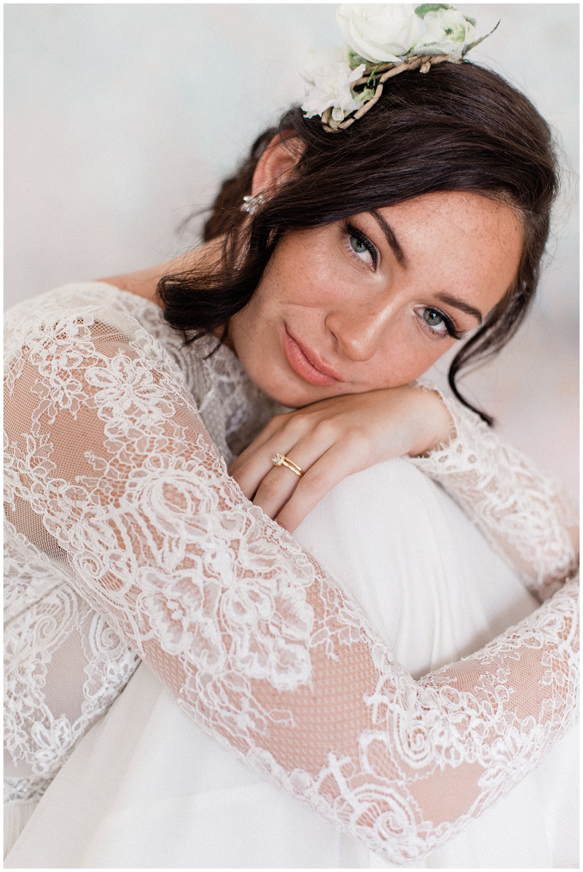 beautiful freckled bride rests her cheek against her knees and shows off her floral headpiece. Images by Comfort and Cashmere. Dear Bride Series about wedding planning.