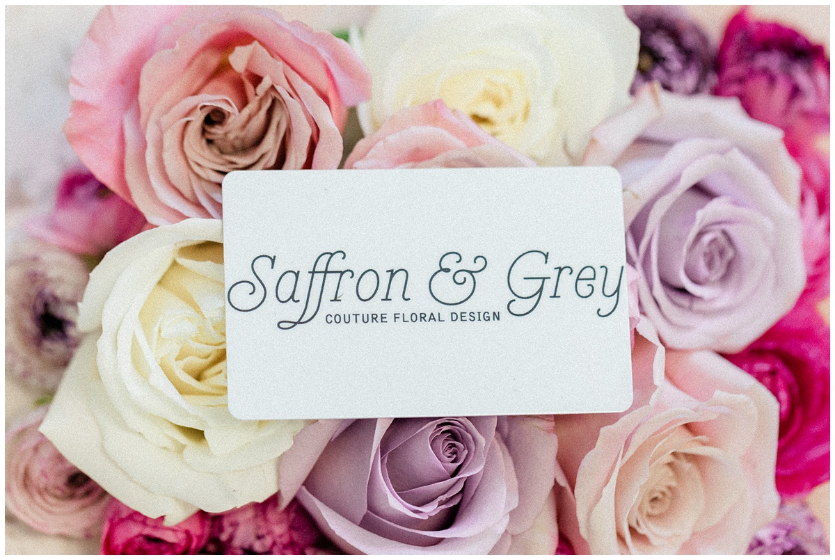 saffron and grey couture floral design business card placed against a variety of roses