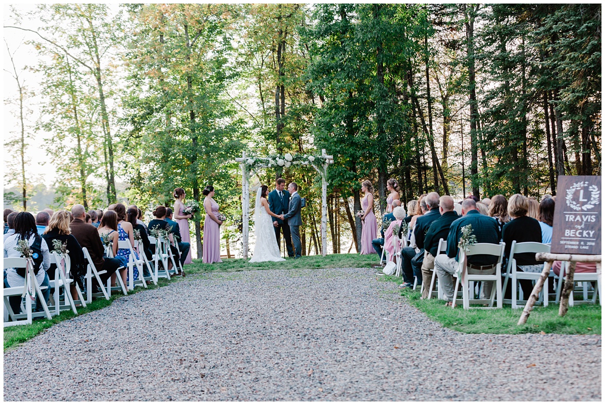 bride and groom are wed outside in a shady spot with trees as a backdrop in Minnesota during summer