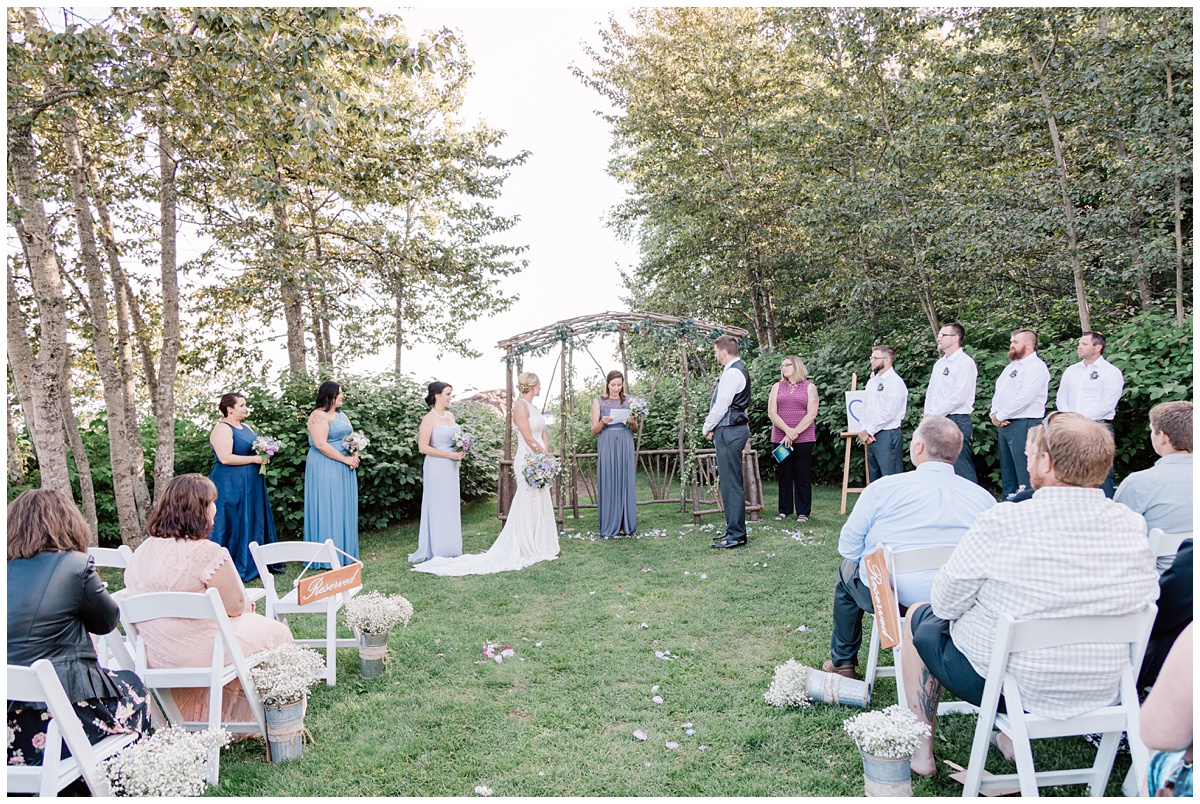 guests look on as a bride and groom begin their outdoor ceremony in Minnesota with a reading by a bridesmaid
