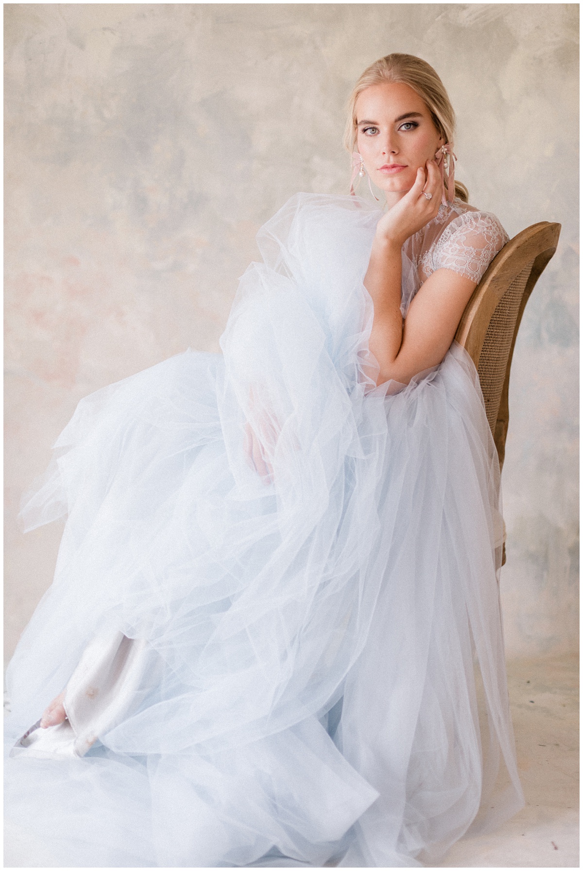 gorgeous blonde bride poses in a chair with her dress splayed all around her. Comfort and Cashmere Weddings.