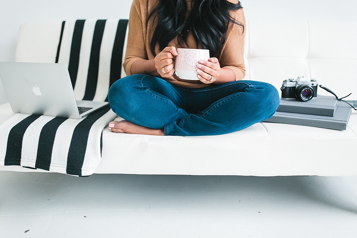 Photographer Rohana Olson of Comfort and Cashmere Images sitting on a couch while holding a cup of coffee and discussing her top work from home tips to stay productive