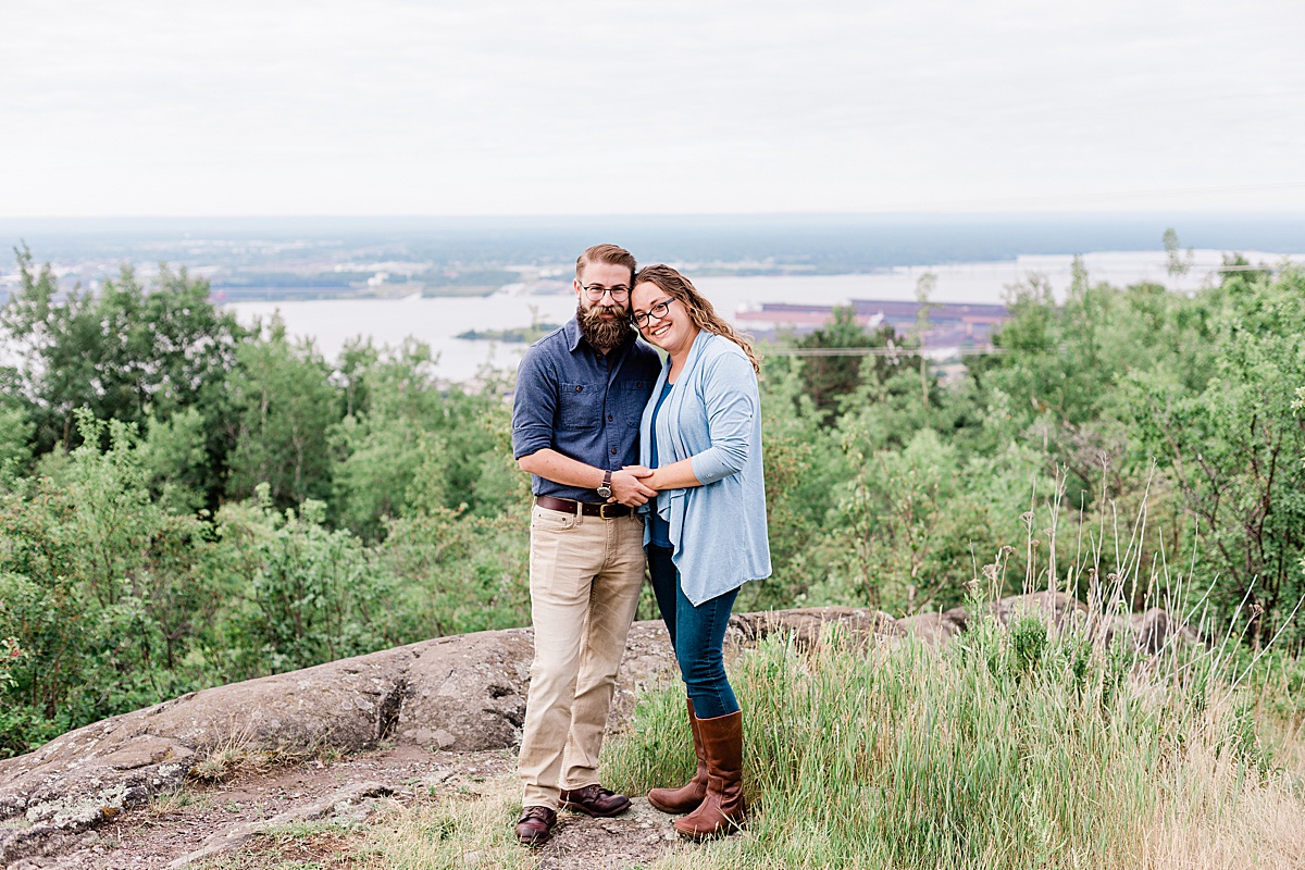 newly engaged man and woman stand together, holding hands at Enger Tower Park in Duluth during a morning engagement session with Comfort and Cashmere Images