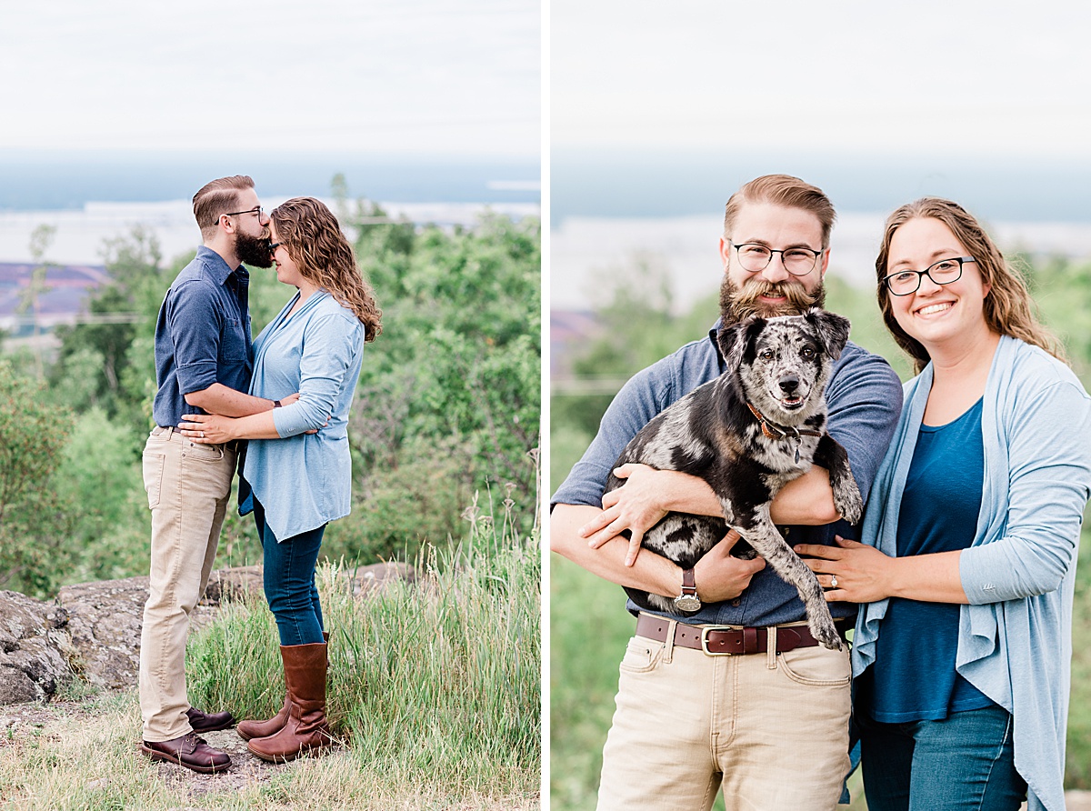 a bearded white man kisses his fiancee's forehead and then the two of them pose with their mini aussie during a morning engagement session at Enger Tower Park in Duluth.