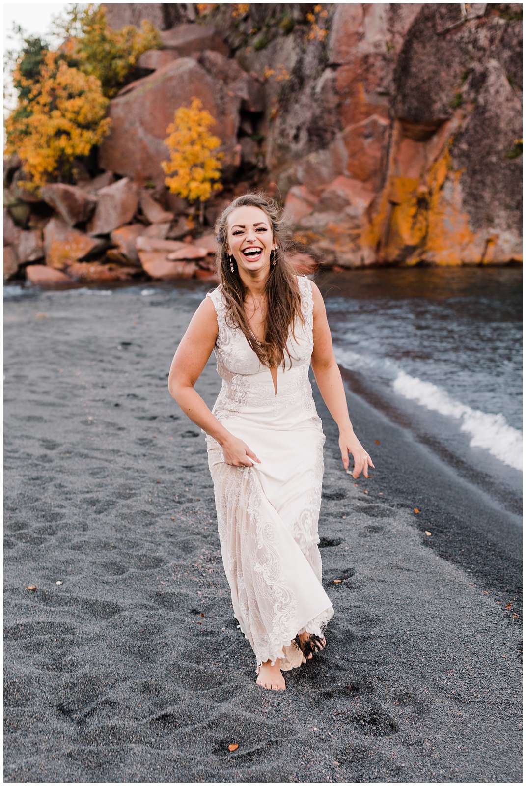 a bride walks along Minnesota's black beach in her bare feet laughing and happy