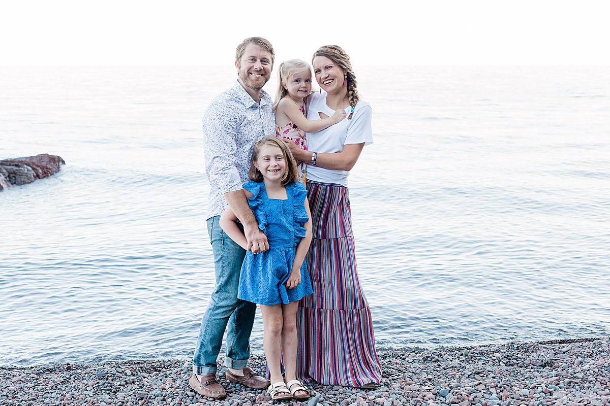 a happy family smiles during their sunset family photo session on the shore of Lake Superior with Comfort & Cashmere images