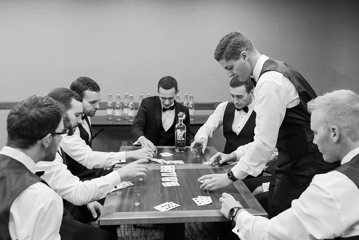 A group of groomsmen play poker and enjoy a drink together before a Clyde Iron Works wedding in Duluth, MN.