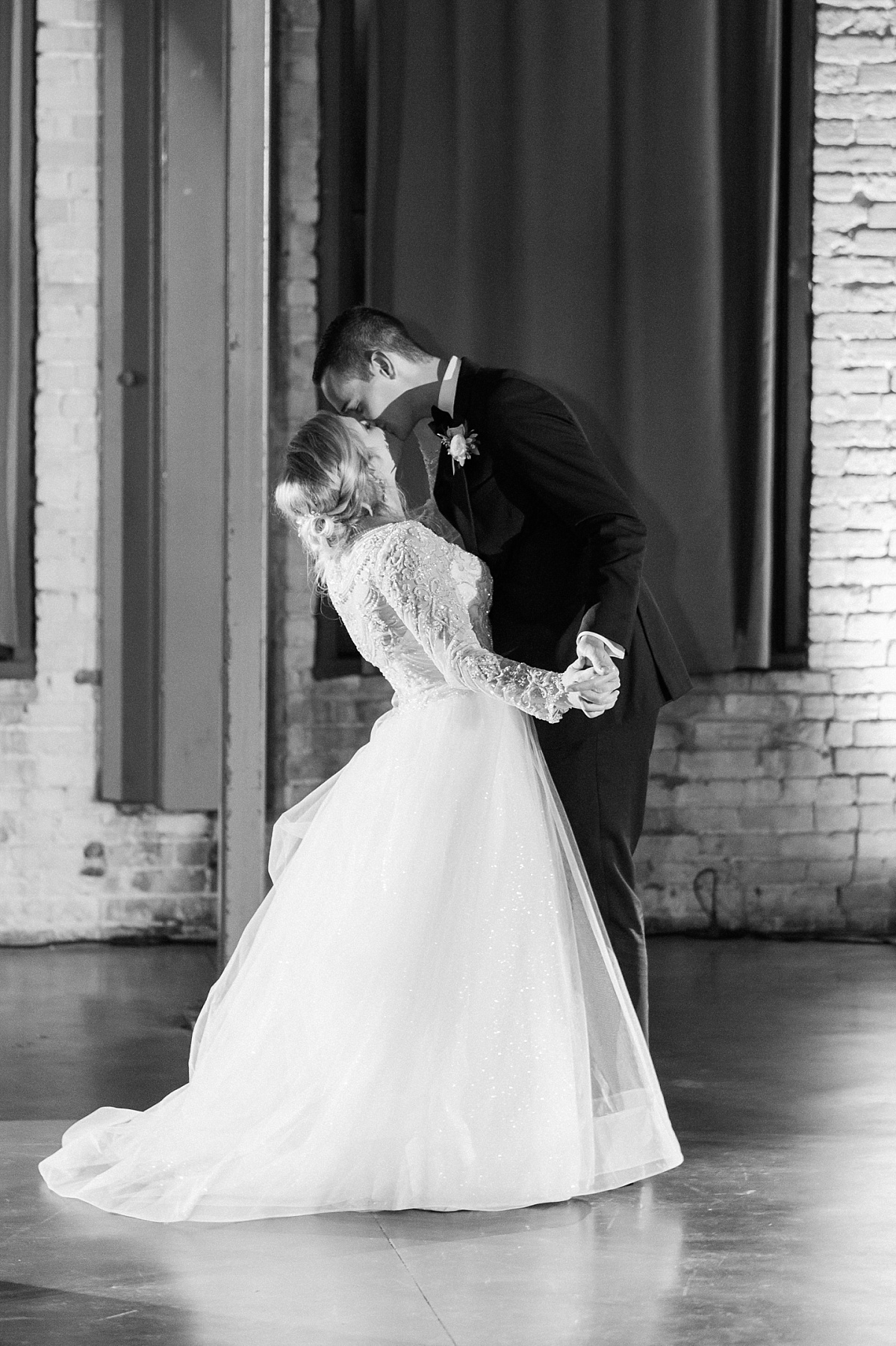 A bride and groom kiss during their first dance at their wedding in Duluth, Minnesota wedding venue Clyde Iron Works.