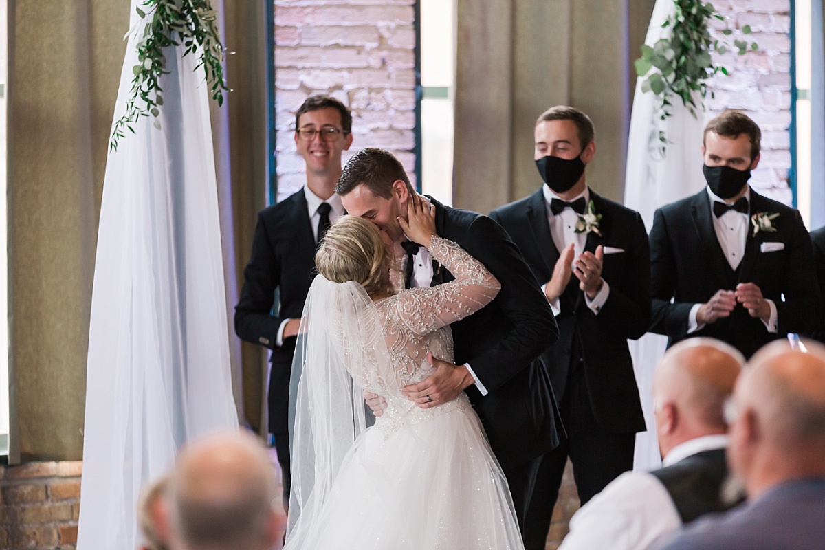 A bride and groom have their first kiss at their Clyde Iron Works wedding in Minnesota.