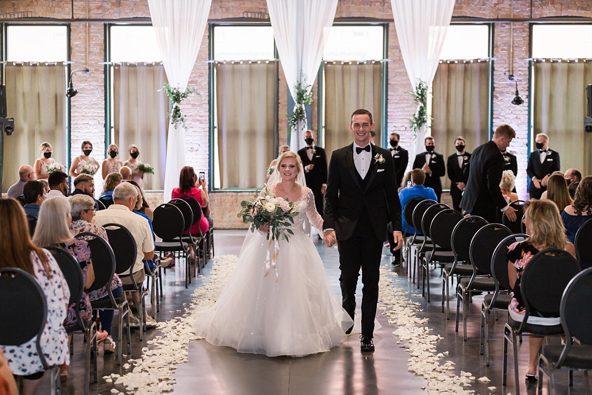 A newlywed couple walks down the aisle at Minnesota wedding venue Clyde Iron Works. 