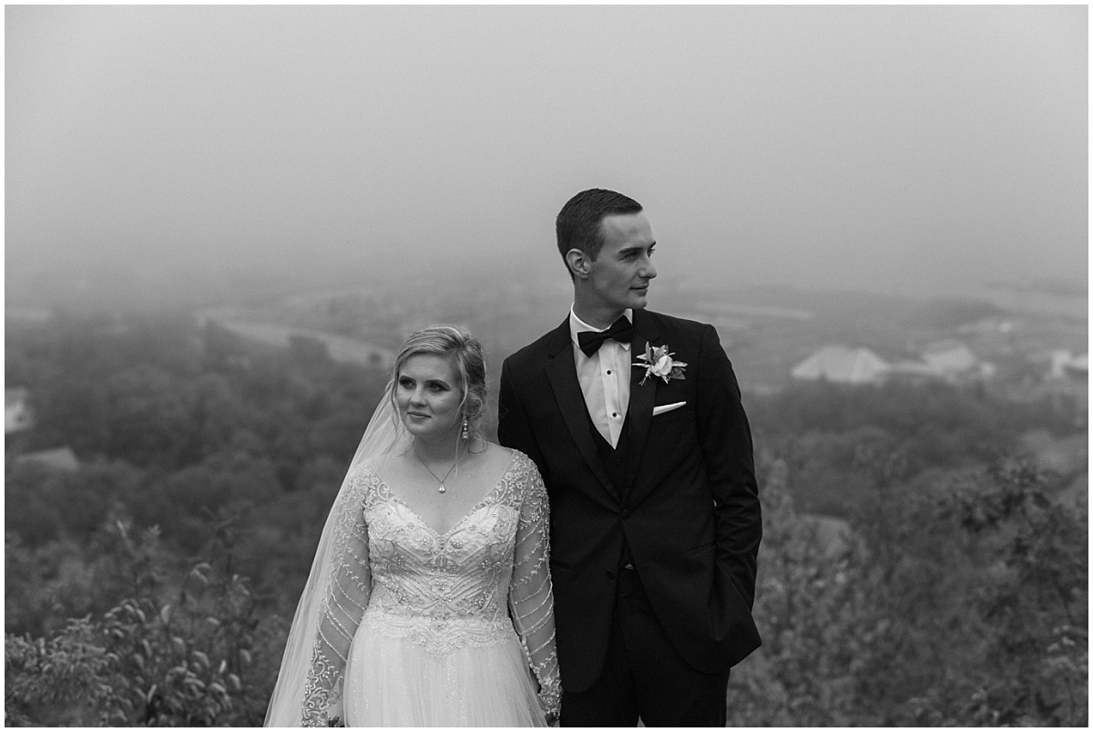 A bride and groom stand side-by-side-looking away from each other, with Duluth in the background.