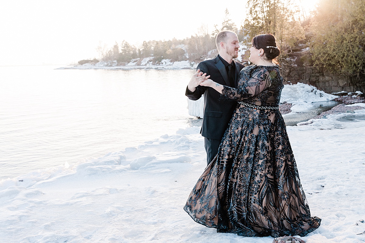 newlywed bride and groom dance on the snowy shoreline of frozen lake michigan with comfort and cashmere images
