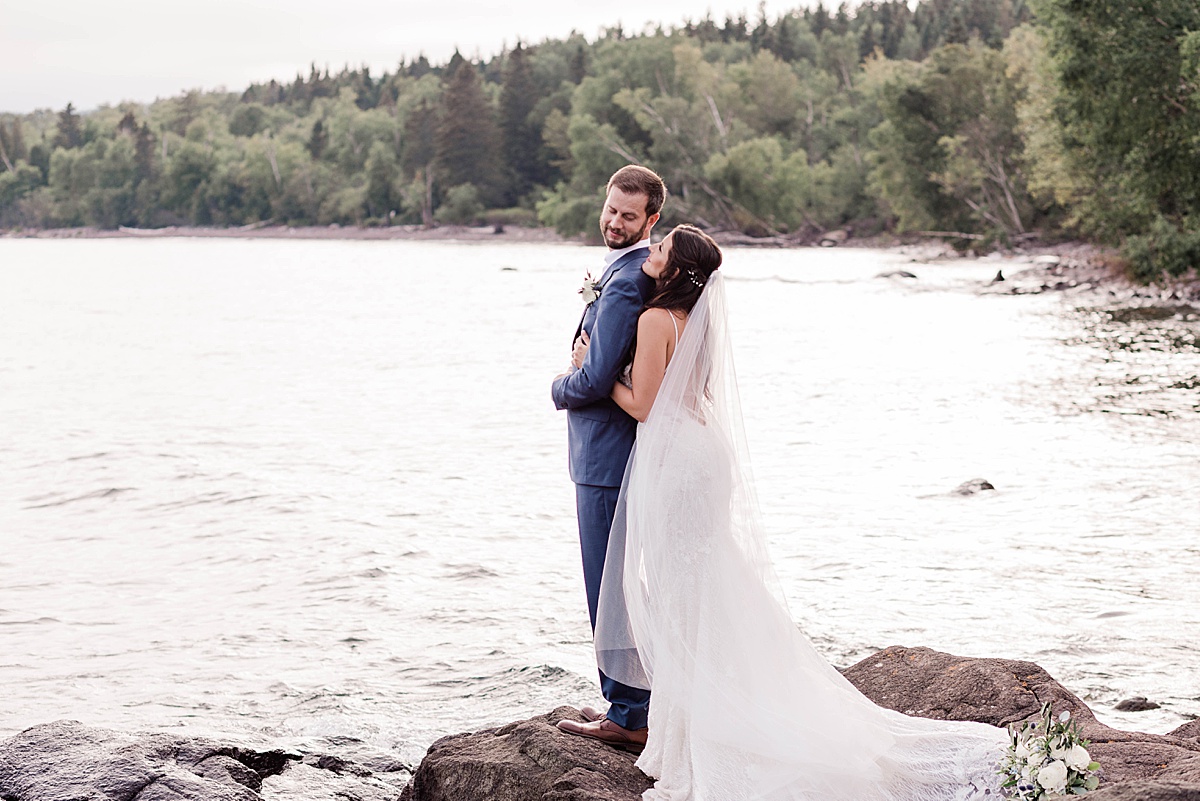 Couple standing by Lake Superior looking at each other.