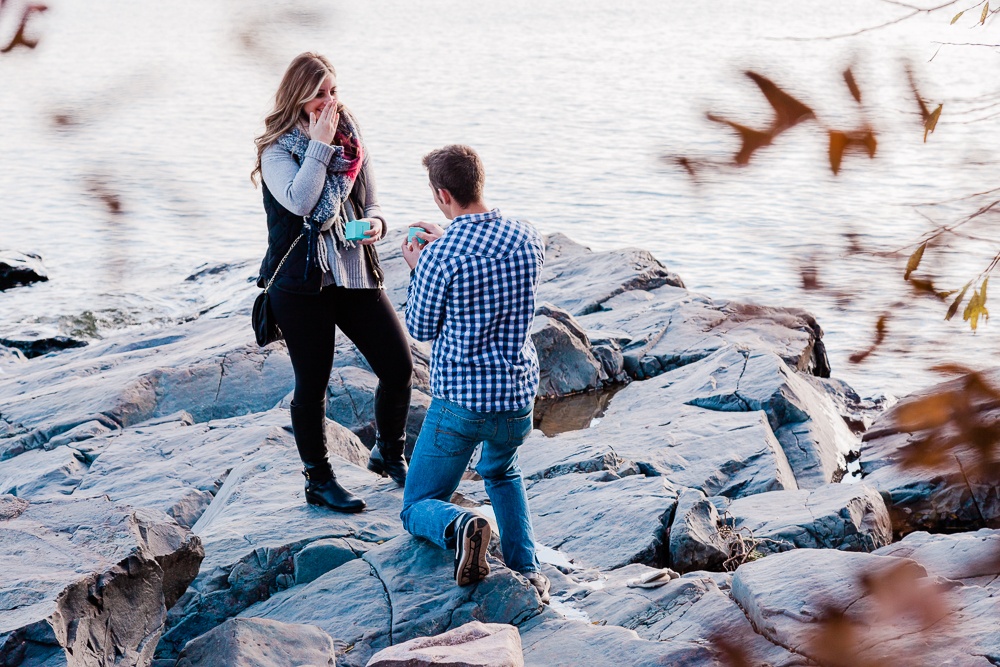 man proposing on one knee to girlfriend with Tiffany and Co engagement ring alongside lake superior