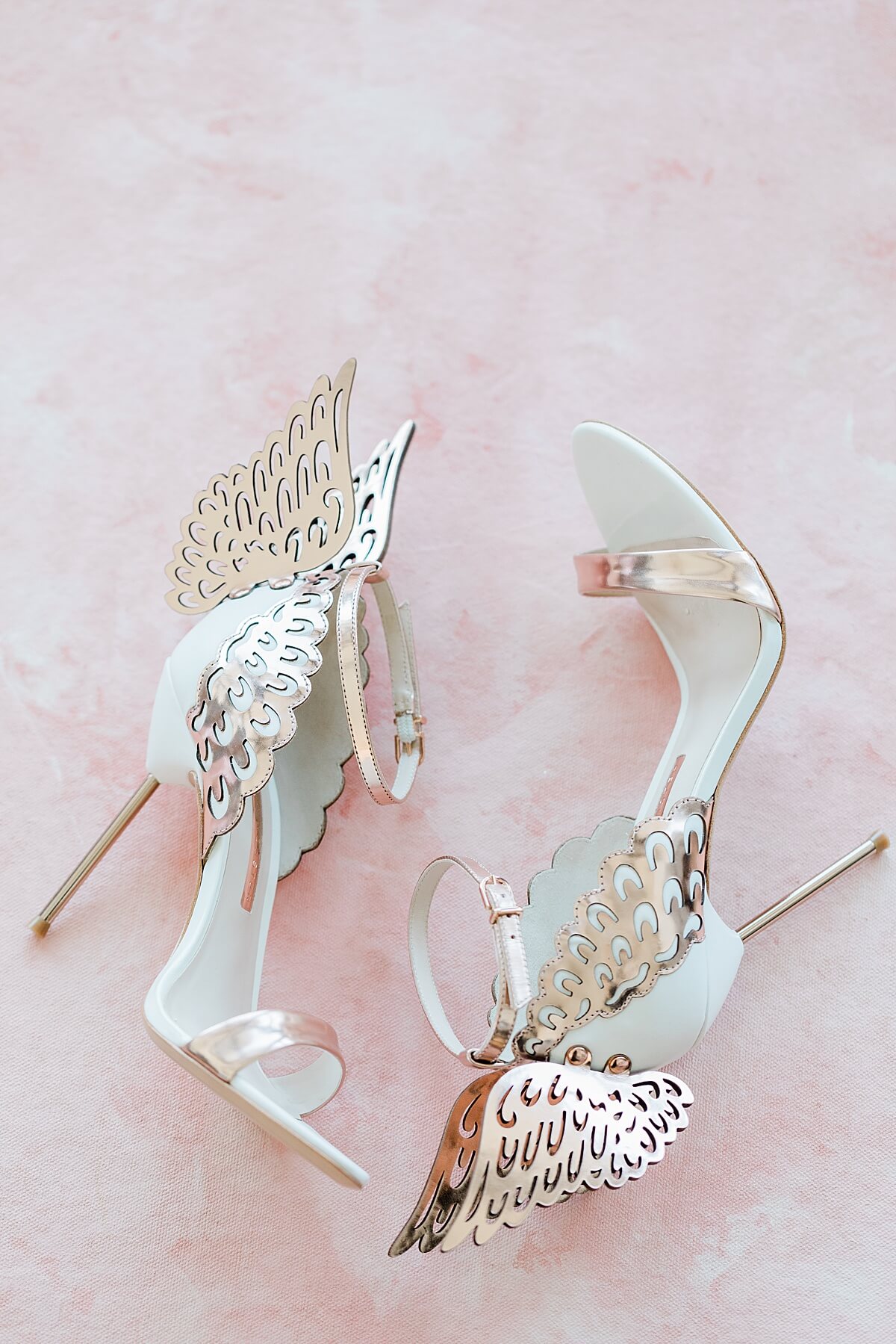 angel wings rose gold high heels on pink backdrop 