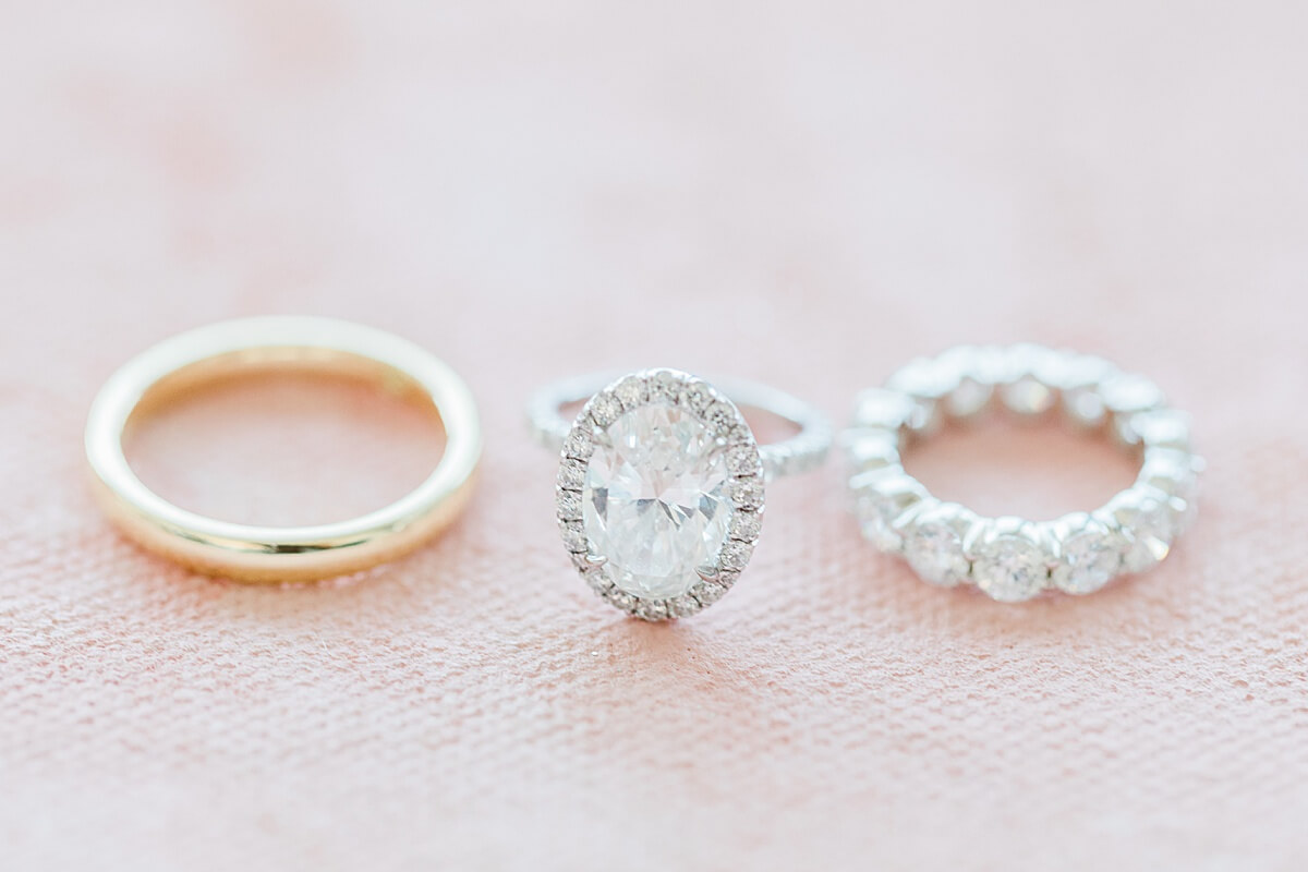 engagement ring, wedding band for bride, and groom next to eachother