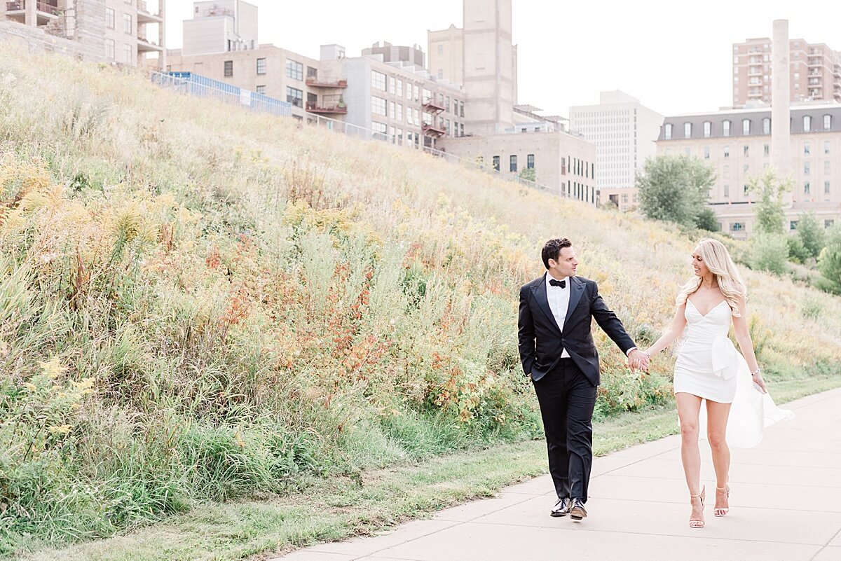 bride and groom walking hand in hand in mill city ruins park 