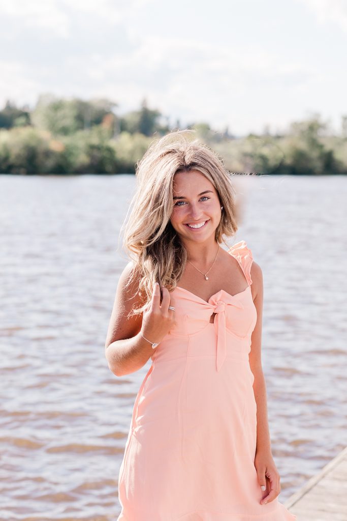 senior girl wearing peach dress standing facing the camera smiling for her duluth senior session