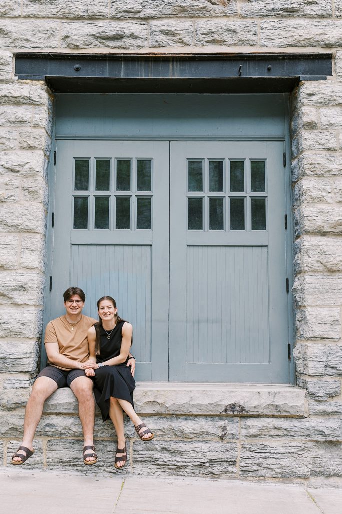 couple sitting at doorway entrance on st. anthony main for their Minneapolis engagement session 