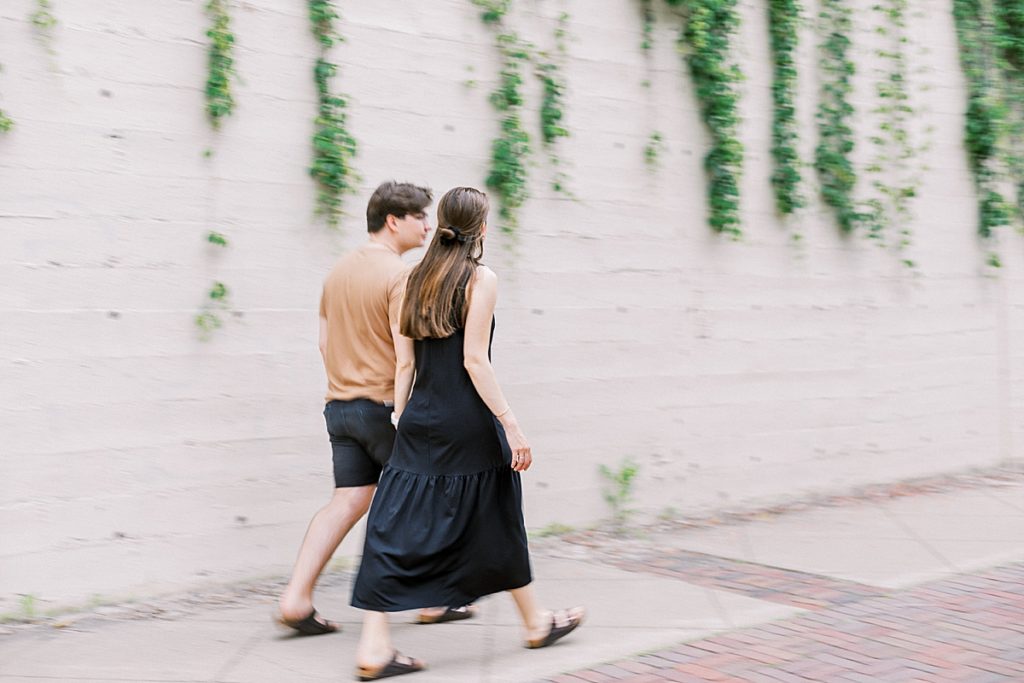 couple walking near white wall on St. Anthony Main in Minneapolis for their engagement session