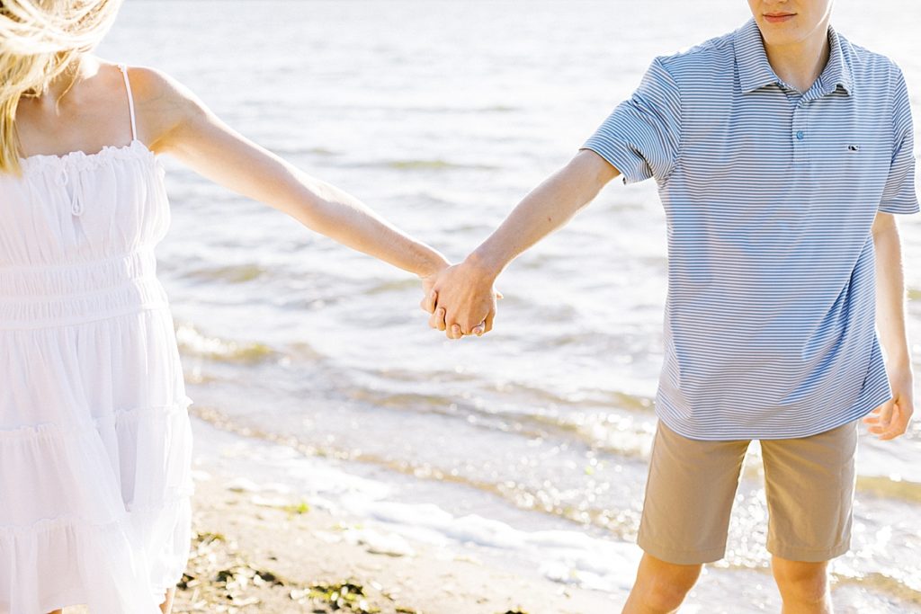 couple holding hands as they walk along the beach 